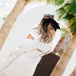 Erin with a low half-ponytail in a bow and a white long cardigan.