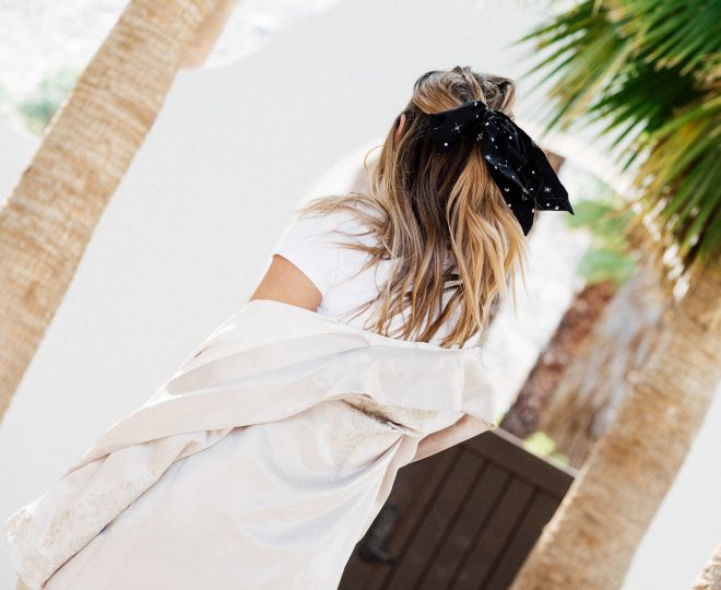 Erin with a low half-ponytail in a bow and a white long cardigan.