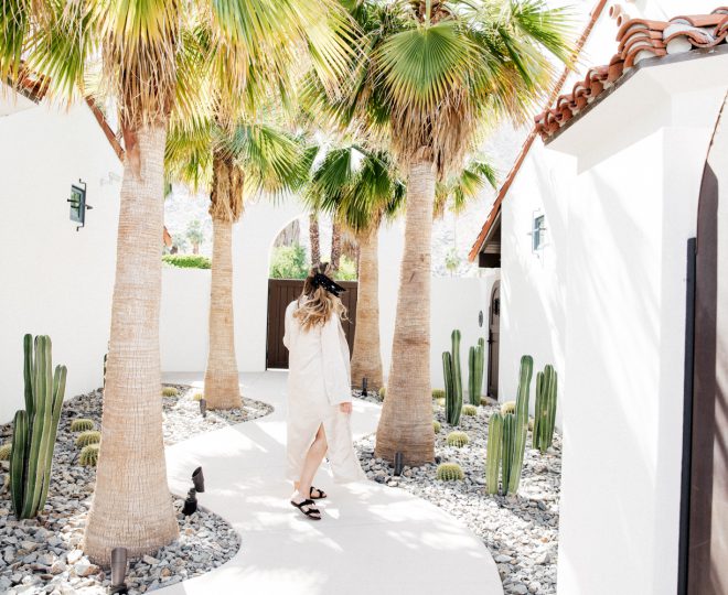 Erin walking in a bright courtyard with cacti and palm trees