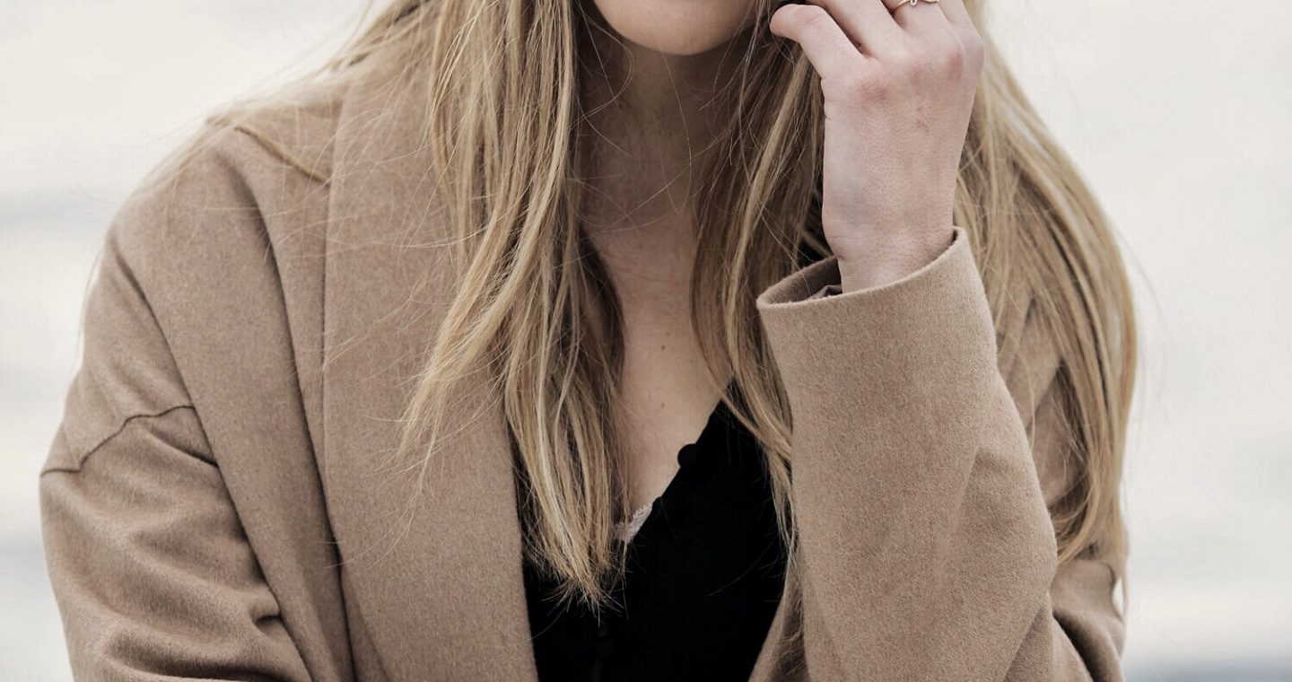 Erin smiling at the camera while wearing an oversized cardigan and statement jewelry.