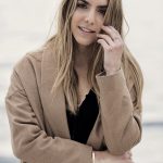 Erin smiling at the camera while wearing an oversized cardigan and statement jewelry.