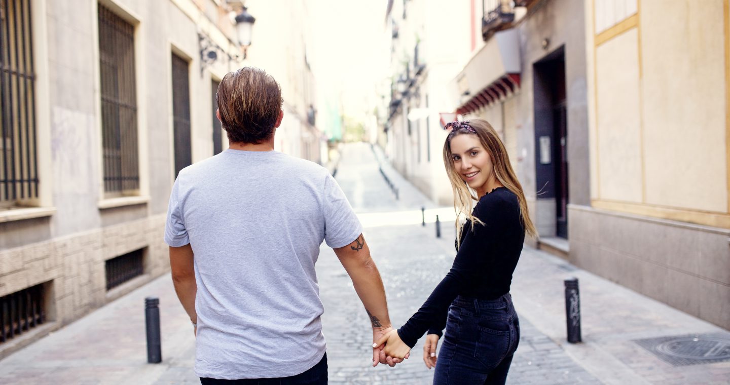 Erin and Matt walking down a street in Madrid and Erin is looking back over her shoulder smiling