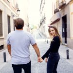 Erin and Matt walking down a street in Madrid and Erin is looking back over her shoulder smiling