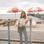 Erin in a floral blouse and checkered pants and a green fanny pack
