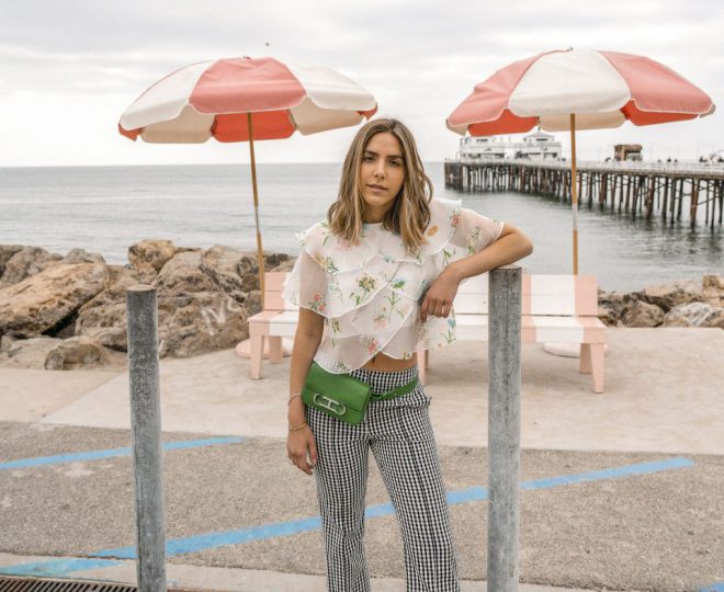 Erin in a floral blouse and checkered pants and a green fanny pack