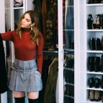 Erin standing in a well organized closet holding up a black jacket.