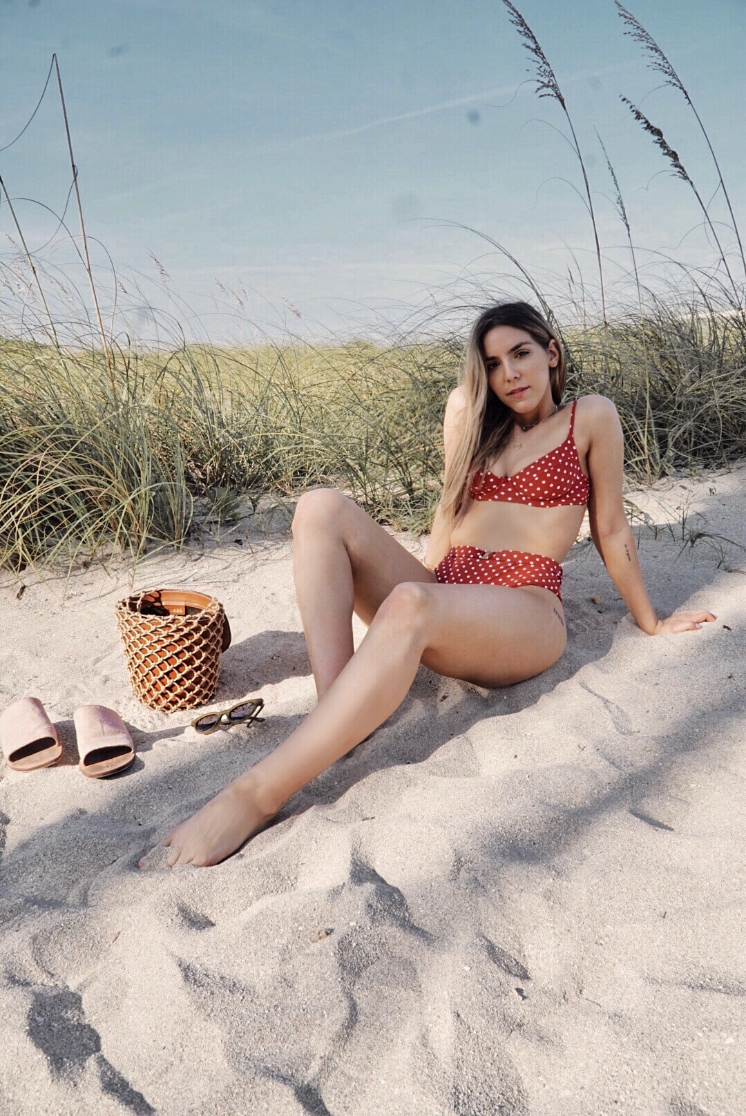 Erin sitting on the sand in a red bikini